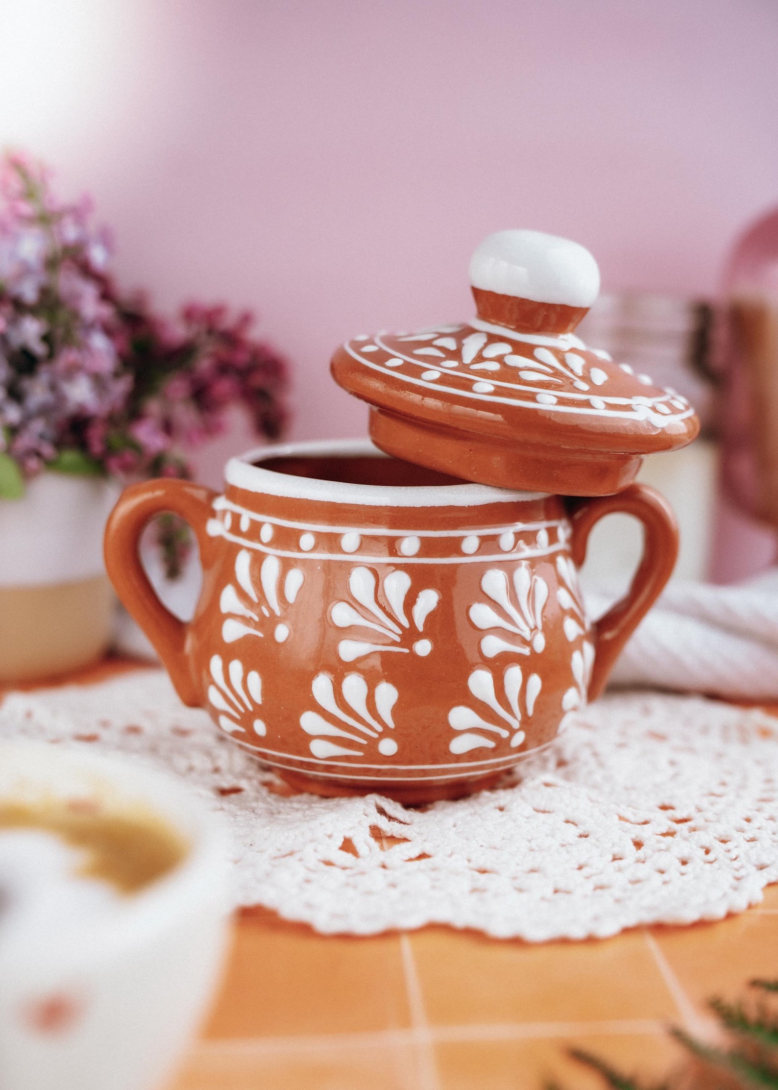 Terakotos cukrinė su baltu gėlių raštu iš arti
